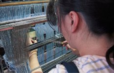 デニムを織りあげていくために、タテ糸一本一本を針金の穴に通していく。3千本の糸を通し終わるのに丸1日かかる