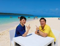 宮古島の輝いている海とまぶしい日差しの中でインタビューをしている野村氏（左）と坂口氏