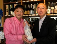 酒蔵で16年熟成させた池島酒造の大吟醸「命」を、池嶋英哲さんが小林一三さんに手渡す