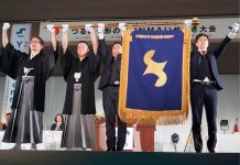 今年２月に開催した全国大会でYEG旗を掲げる（左から）中川誠筆頭副会長、小野知一郎直前会長、吉田昌宜会長、岡田充貴全国大会担当理事