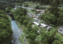 多摩川のほとりにたたずむSatologue（手前に見える２棟）と奥を走る青梅線