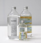 500ミリリットル瓶の表面（左）と裏面（右）、100ミリリットル瓶（中）。ラベルのデザインには、糸魚川の森（緑）、流れる川（青）、それらを照らす陽の光（オレンジ）がイメージされています。